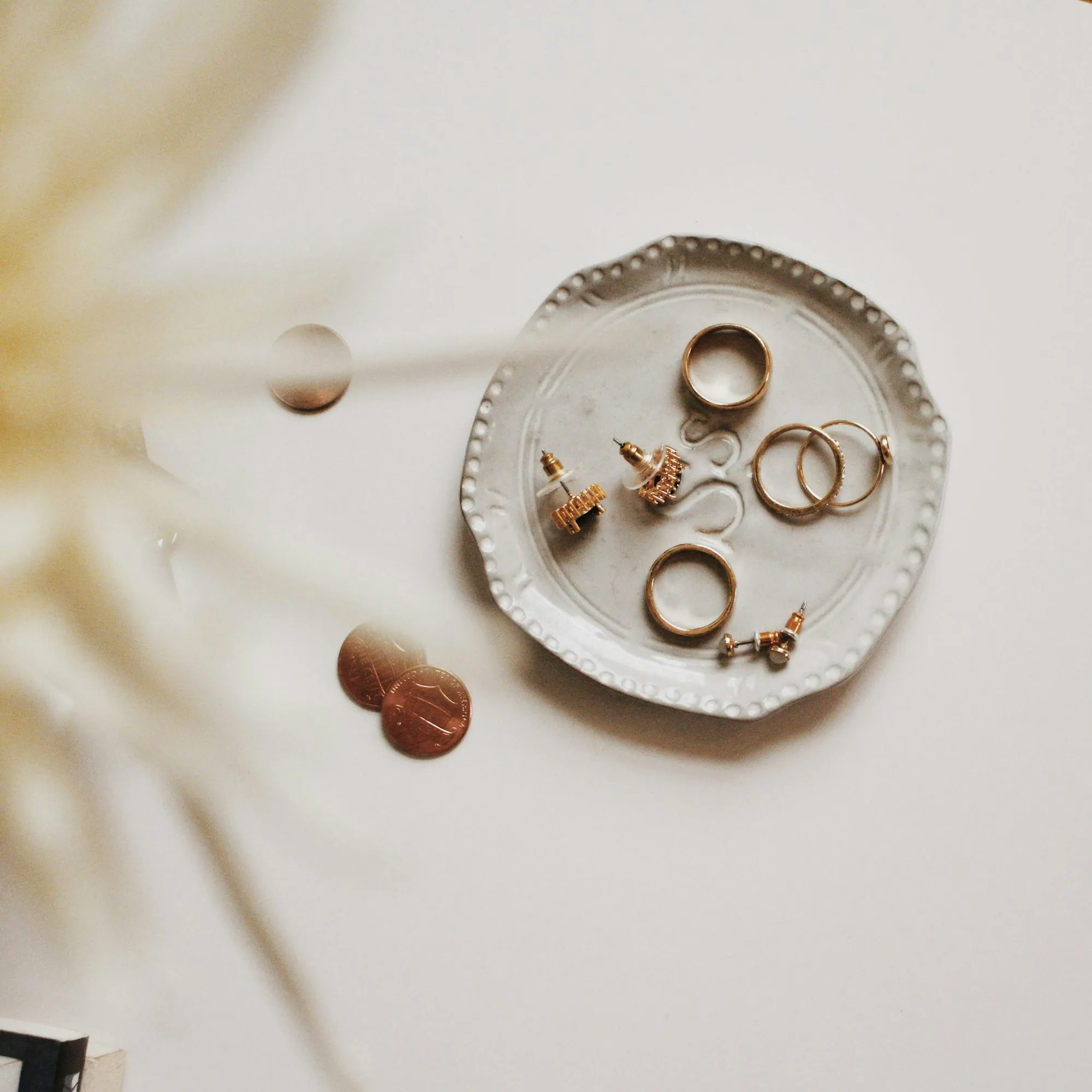 Bagues et boucles d’oreilles dorées dans une coupelle en céramique